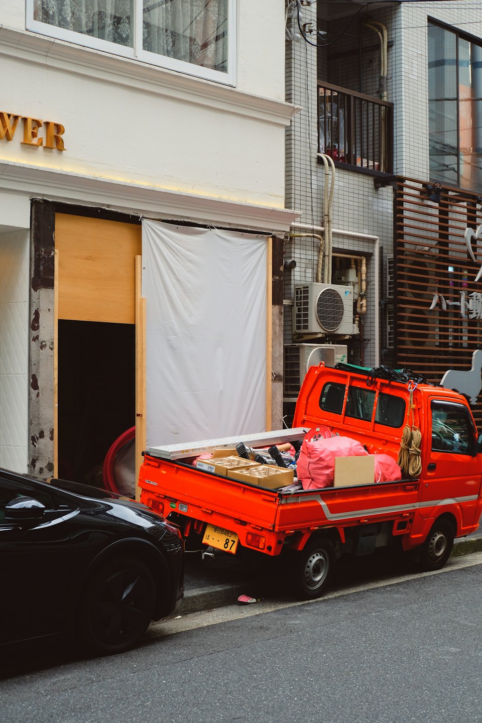 Home Orange mini-truck loaded with boxes and bags on a city street.