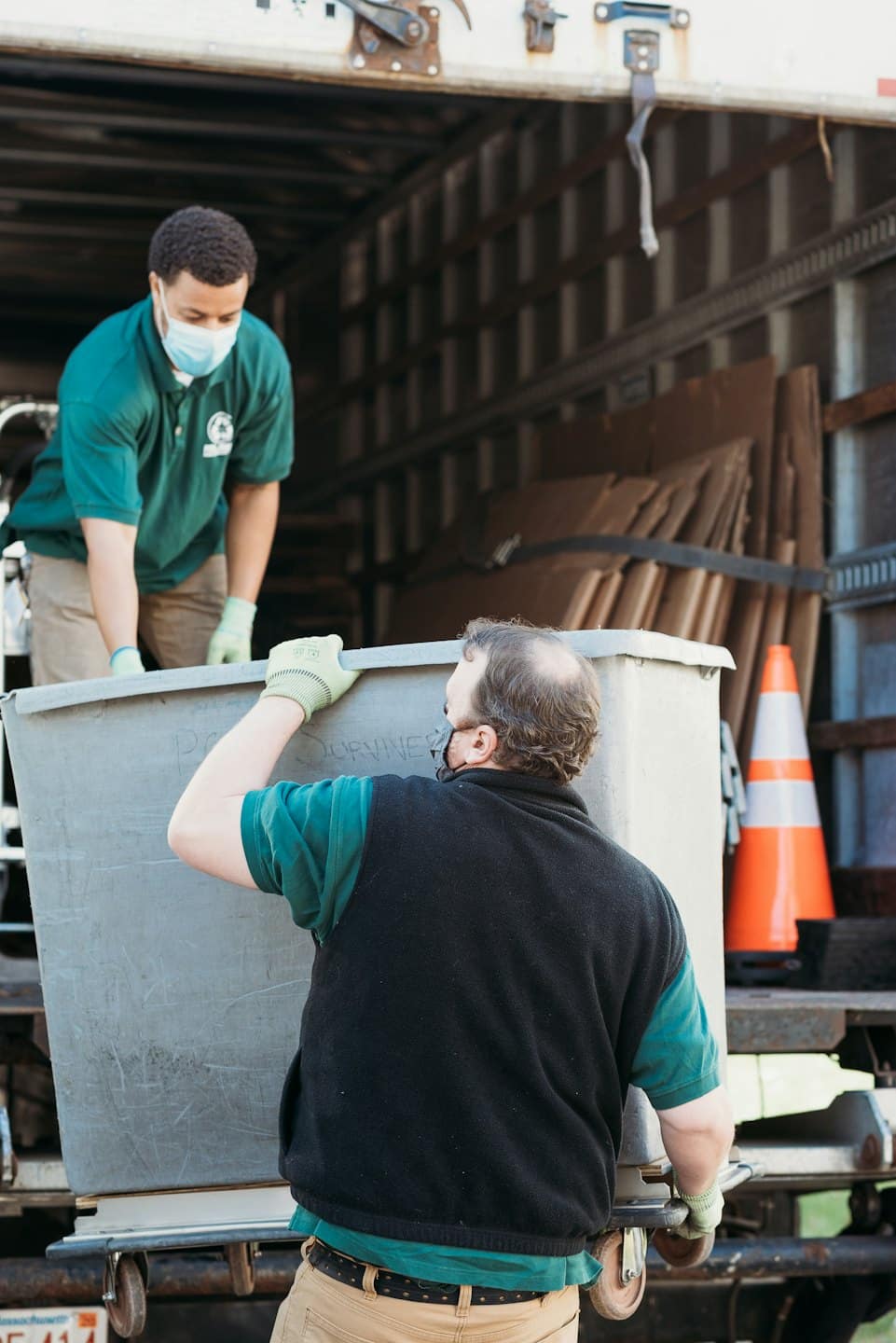 Home Men load a wheeled container into a moving truck.